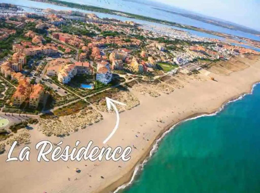 une vue aérienne sur une plage avec les mots la residence dans l'établissement Appartement T2 vue mer port-leucate accès direct plage avec piscine et ascenseur port leucate, à Leucate