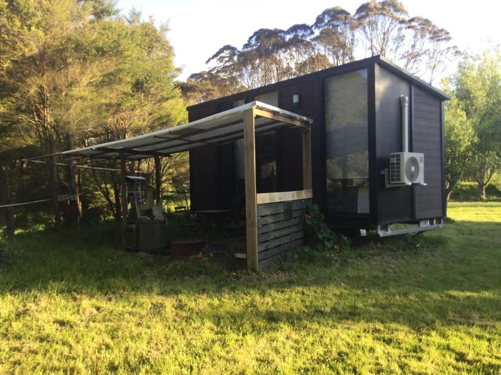 ein schwarzes, kleines Haus auf einem Feld in der Unterkunft Streamside Tiny House in Mangatarata