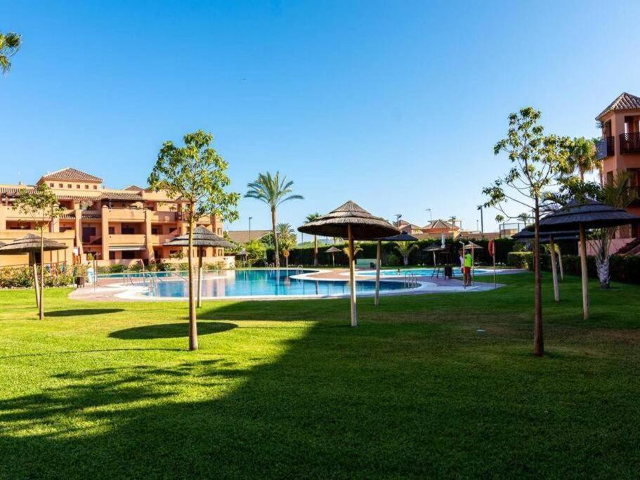 a park with umbrellas and a swimming pool at Albatros Apartamentos Playa Granada in Motril