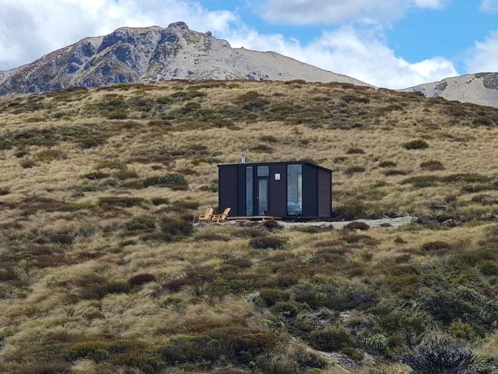 ein schwarzes Haus auf einem Hügel mit einem Berg im Hintergrund in der Unterkunft Lake Stella 1 - Falcons Nest in Mt Lyford