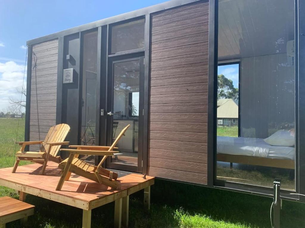 a tiny house with two chairs on a deck at Arariri River Rest in Springston