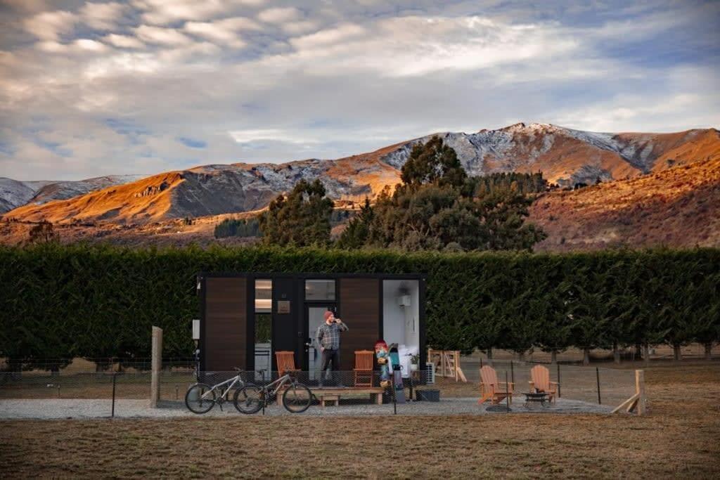 a man standing in a tiny house with mountains in the background at Muddy Hill Moments in Arrowtown