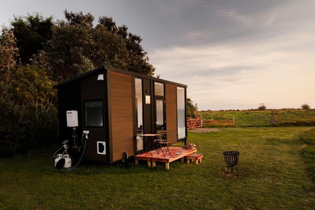 une petite maison assise dans un champ avec un banc dans l'établissement The Coast 1, 