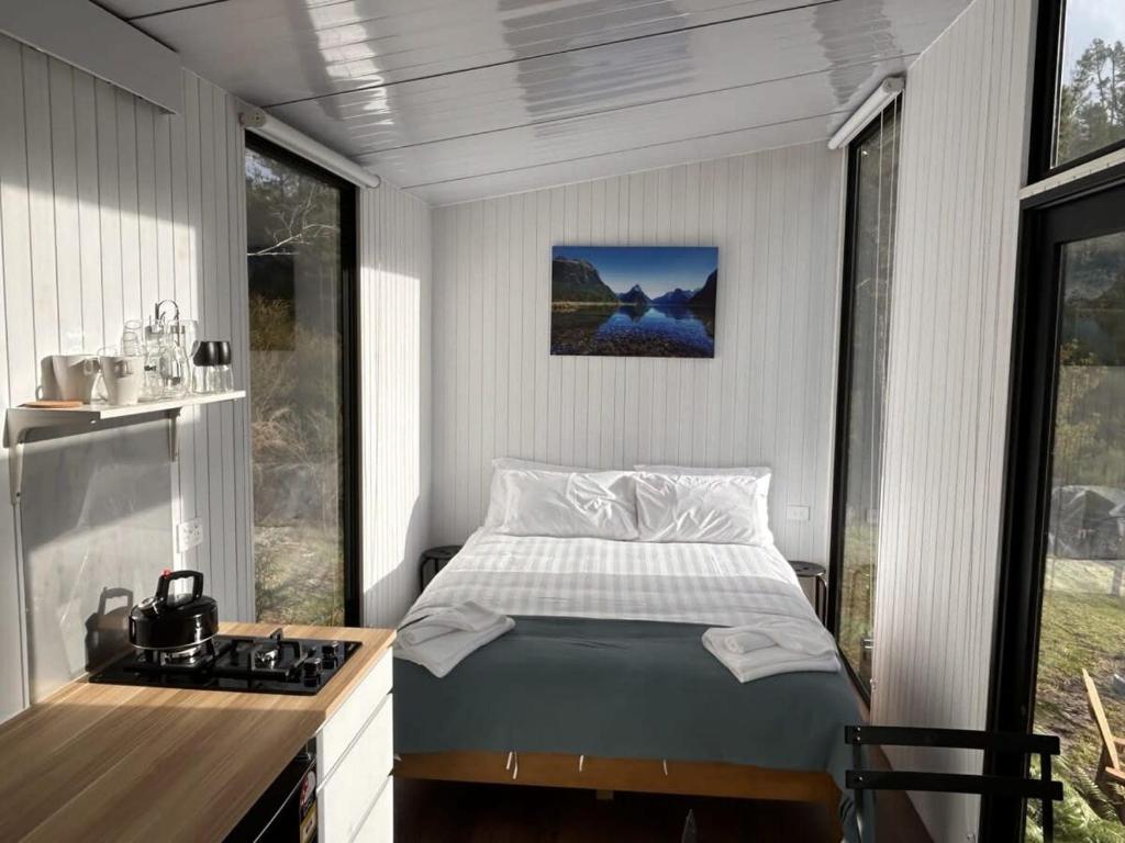 Dormitorio pequeño con cama y fogones en Aroha Tiny House, en Rangihaeata