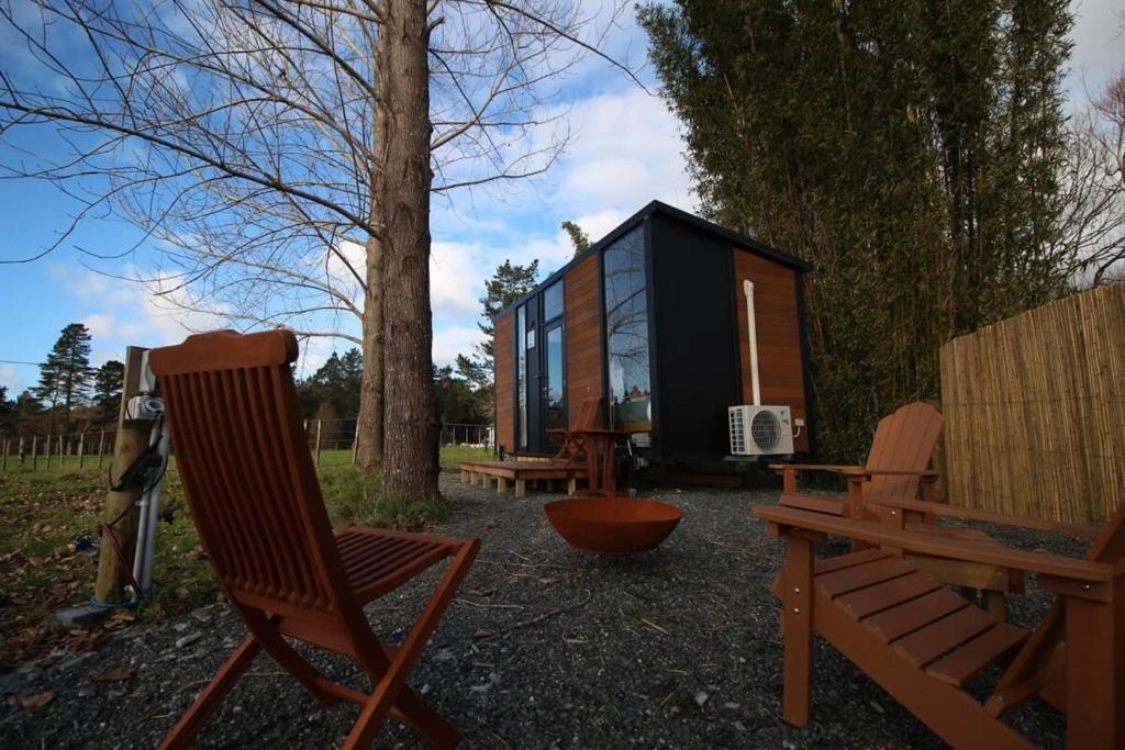 a couple of chairs sitting in front of a tiny house at Breathe Inn in Kaitaia