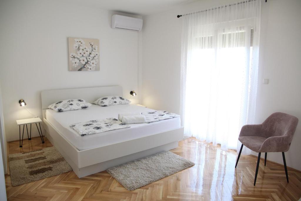 een witte slaapkamer met een bed en een stoel bij Rooms Kresan in Zadar