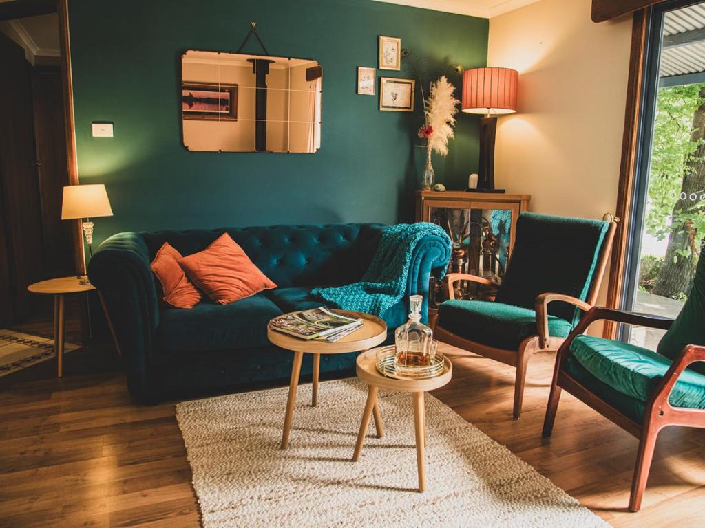uma sala de estar com um sofá azul e cadeiras em Snowy Valleys iconic stay - Moonshiner Cottage @ Distillery em Tumbarumba
