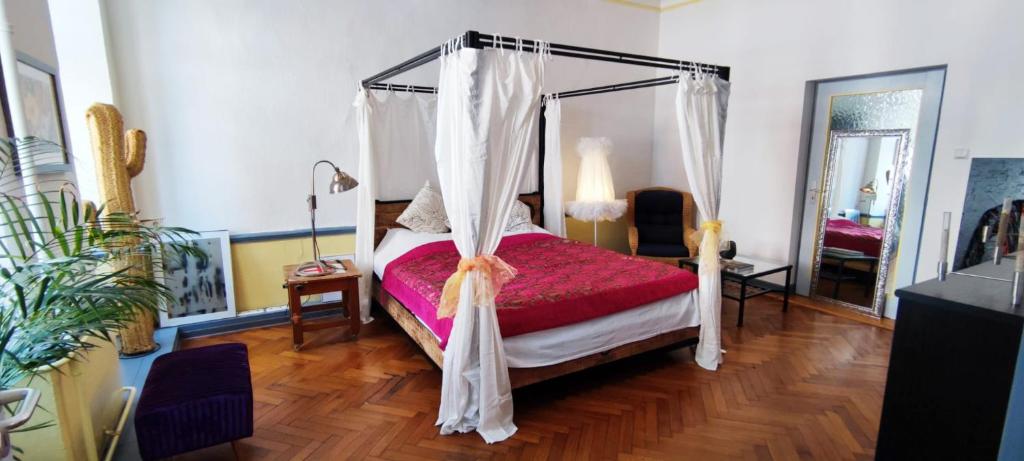 1 dormitorio con cama con dosel y edredón rojo en Designwohnung am Schloss en Weilburg