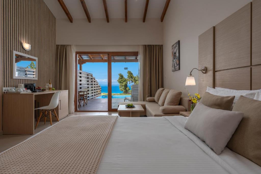 a bedroom with a bed and a desk with a view of the ocean at Alia Palace Hotel - Adults Only 16+ in Pefkochori