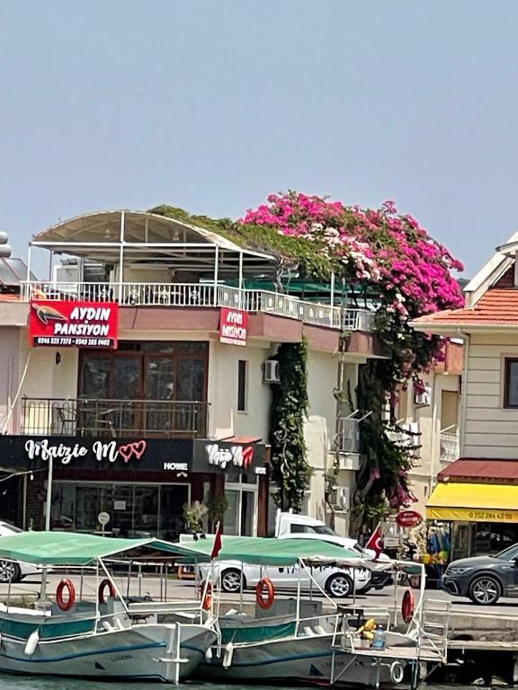a boat parked in front of a building with flowers at Aydın Pansiyon in Ortaca