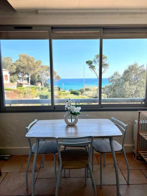 une table avec des chaises et un vase avec des fleurs dessus dans l'établissement Miroir de la mer, appartement vue mer pied dans l eau, à Fréjus