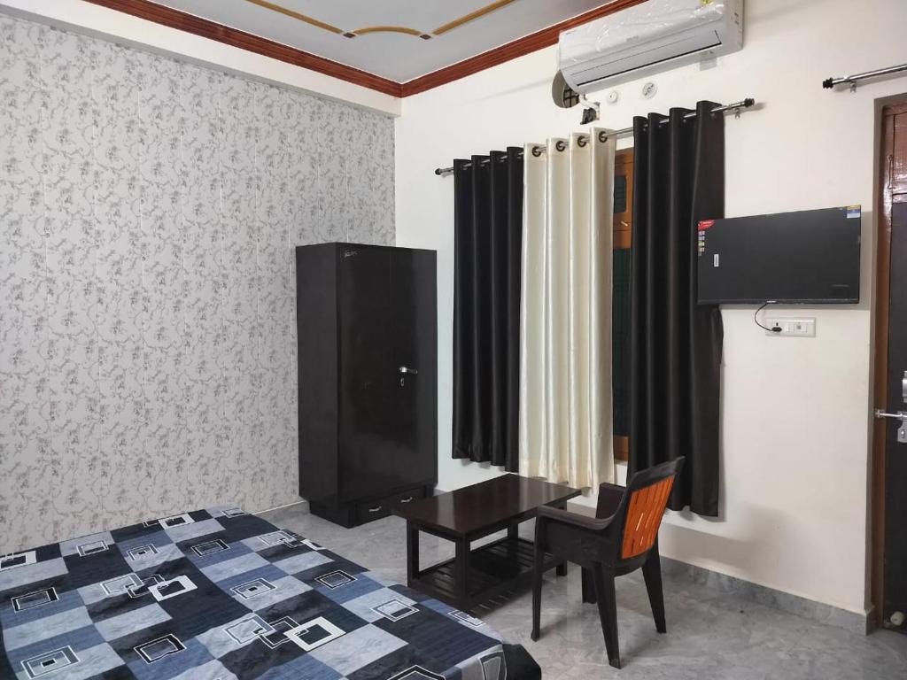 una camera con letto, scrivania e TV di Hari Om Homestay a Faizābād