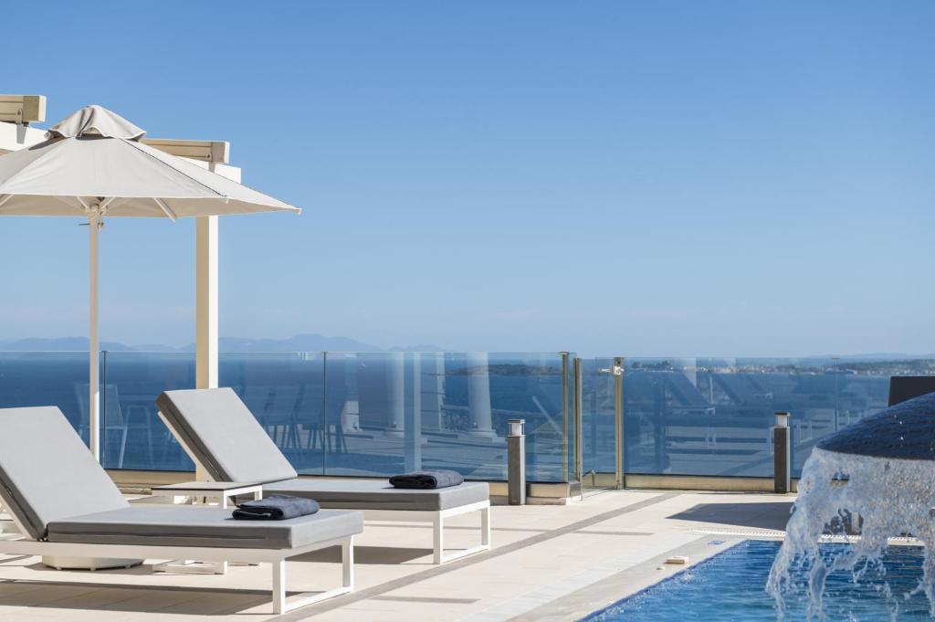a pool with two lounge chairs and an umbrella at Villa Monte Leone by Konnect with Pool, Hot Tub, Spa Room & Stunning Seaview in Pyrgi