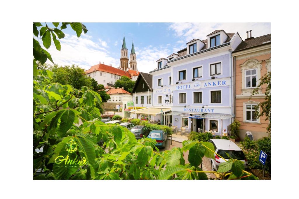 a town with cars parked on a street with a church at Hotel Anker in Klosterneuburg