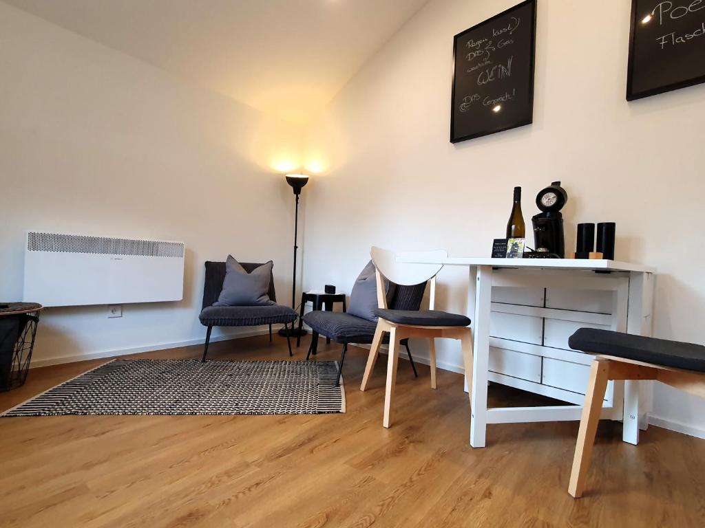 Habitación con mesa blanca, sillas y pizarra en Ferienapartment Rebwinkel, en Burgen