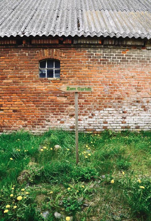 a sign in the grass in front of a brick building at Apfelhof Biesenbrow in Biesenbrow