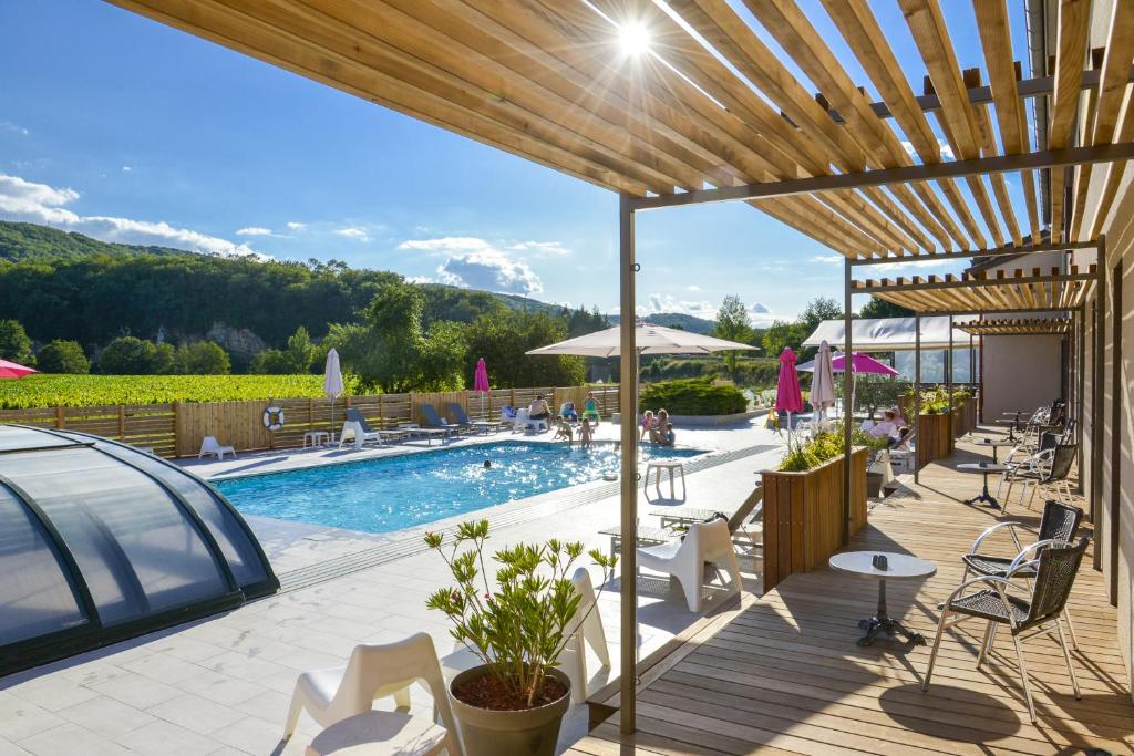 een patio met een zwembad en tafels en stoelen bij Hôtel Les Gabarres in Tour-de-Faure