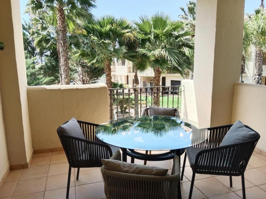 a patio with a table and chairs and palm trees at El Oasis de Roda Golf Apartment in San Javier