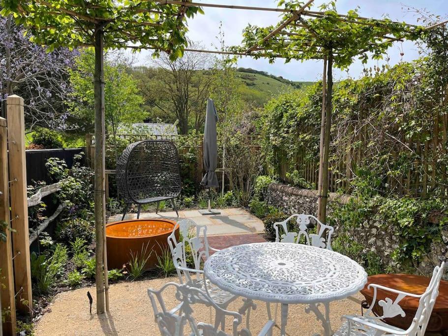 un patio con mesa, sillas y sombrilla en South Downs Cottage With Views, en Poynings