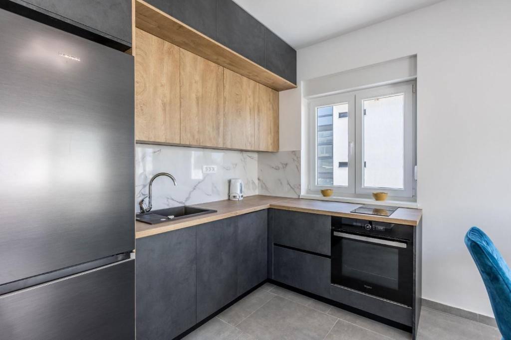 a kitchen with wooden cabinets and a sink and a window at Villa Carpe Diem Rogoznica in Zečevo