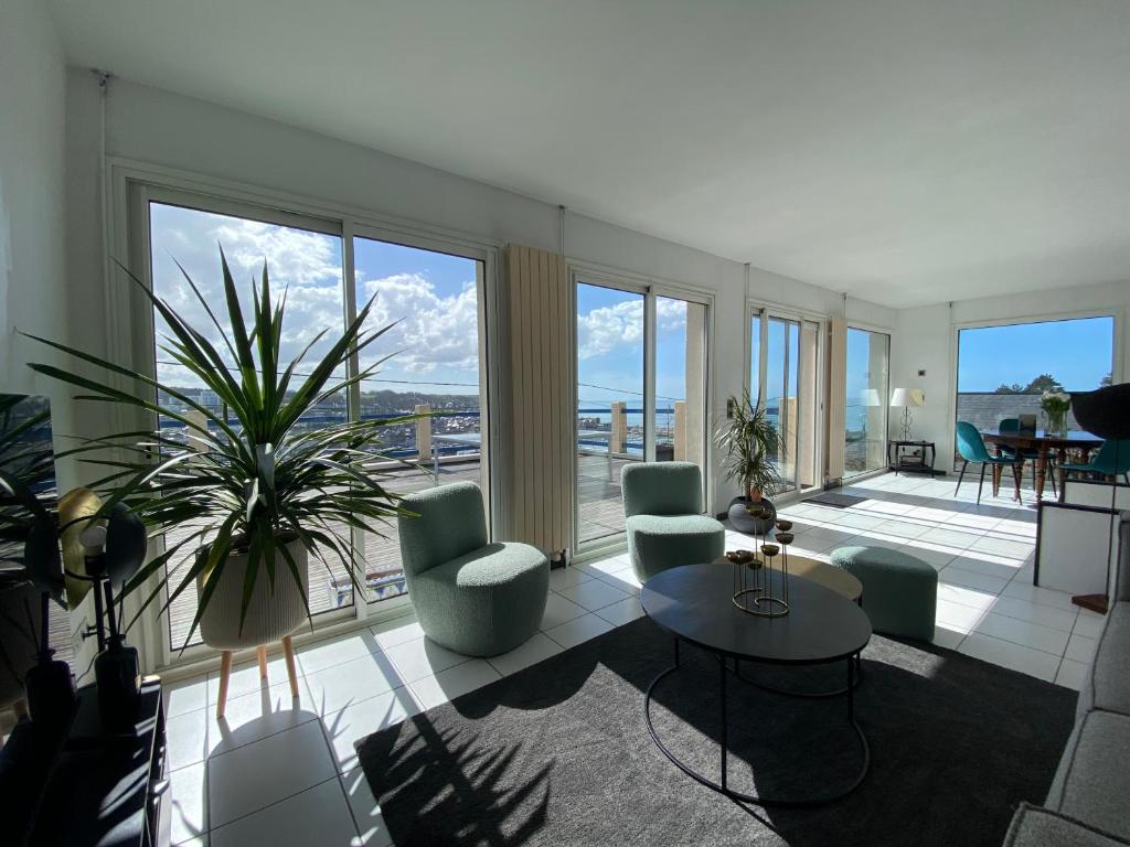 un salon avec des chaises, une table et des fenêtres dans l'établissement Maison vue mer, port et ville, à Fécamp