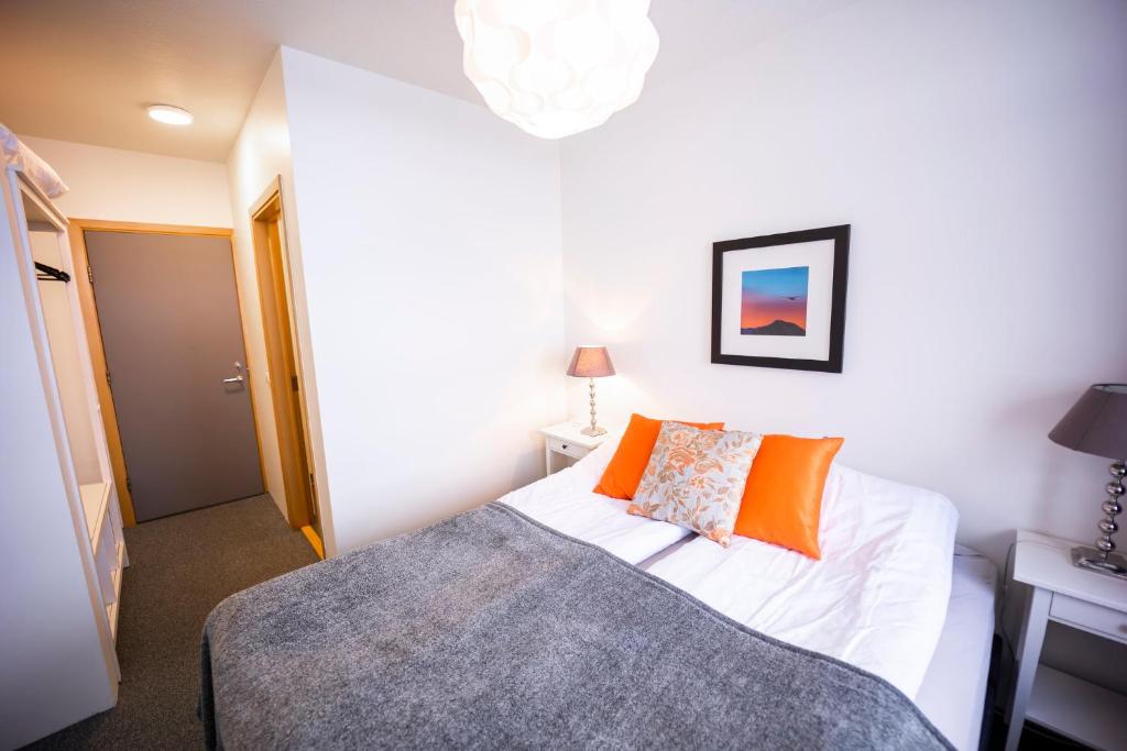 een slaapkamer met een bed met een oranje kussen bij The Northern Comfort Inn in Ólafsfjörður