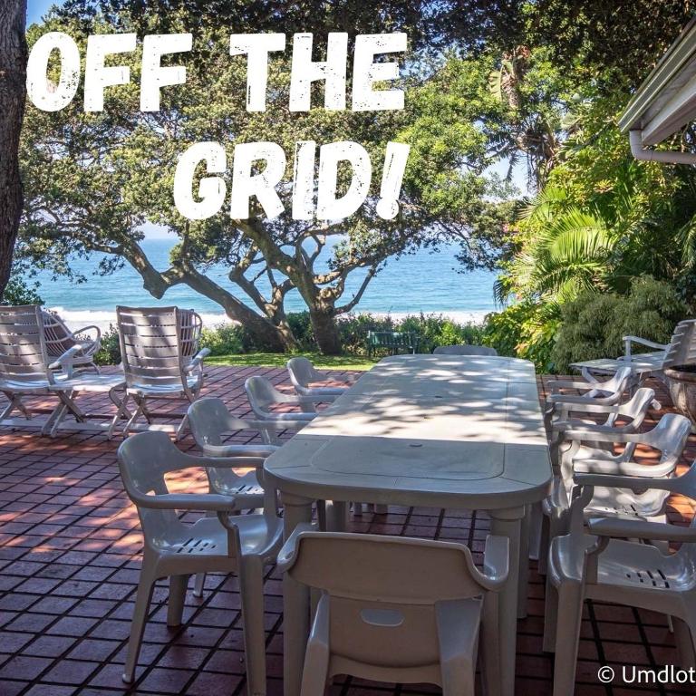 a table and chairs with the words off the grid at Kwa Thibi Cottage Sleeps 14-with inverter in Umdloti