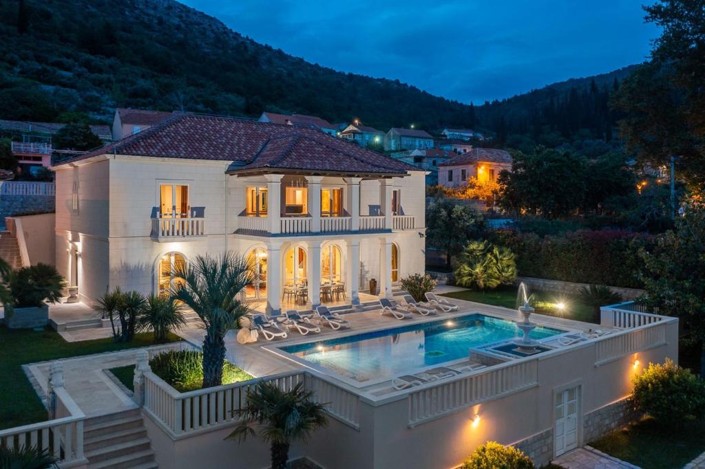 una casa con piscina por la noche en La Villa Dubrovnik, en Trsteno