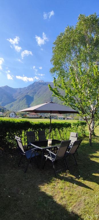 a table and chairs with an umbrella on the grass at Apartma Soča Oasis in Srpenica