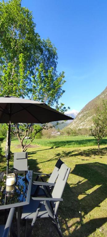 a table and chairs under an umbrella in a field at Apartma Soča Oasis in Srpenica