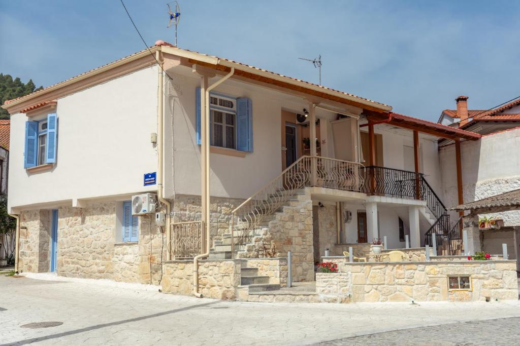 a white house with a stone wall and stairs at Patriko Retro House in Fourka