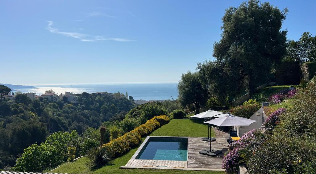 una piscina all'aperto con ombrellone e oceano di La Coulina a Nizza