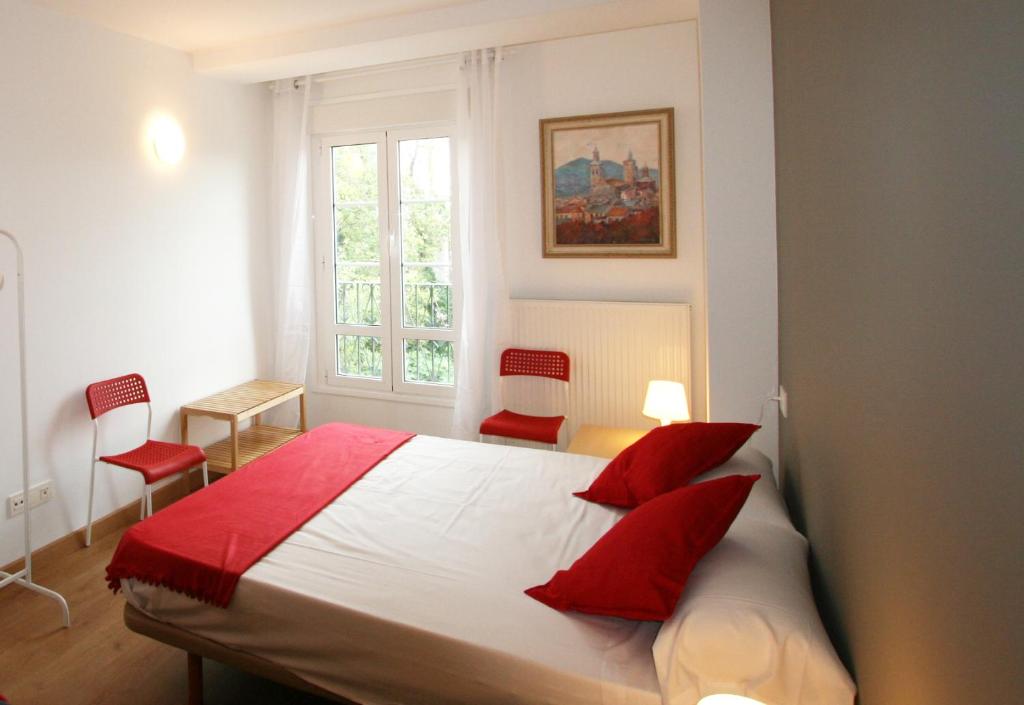 een slaapkamer met een groot bed met rode kussens bij Apartamento Labegain 1 in Sestao