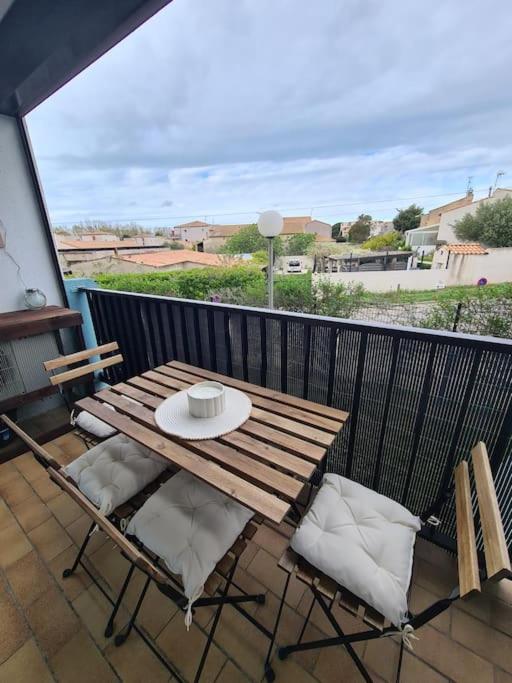 une table et des chaises en bois sur un balcon dans l'établissement Magnifique T2 - Le Lagon bleu, au Grau-du-Roi