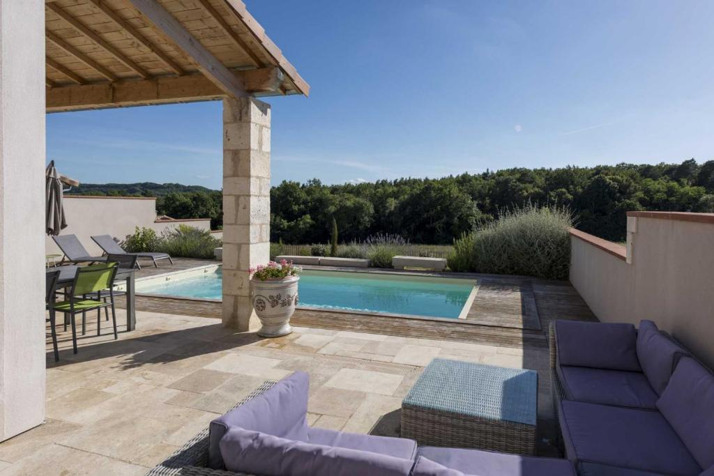 um pátio com piscina e cadeiras e uma casa em La Durantie - Villas avec piscine em Castelnau-de-Montmiral