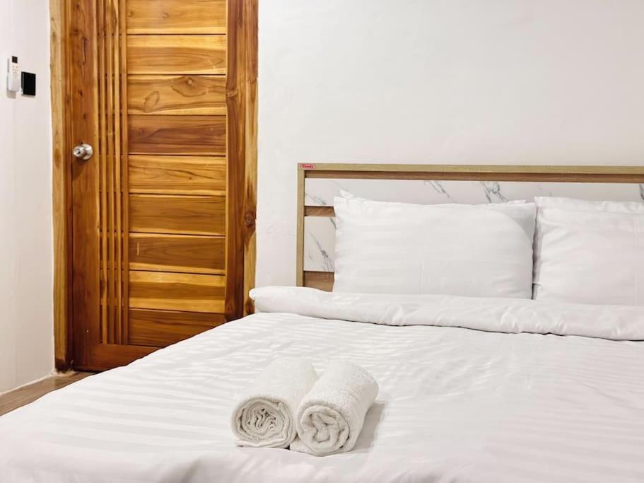 Una cama blanca con dos toallas encima. en Chubby 5 Room 4 en Ban Bang Bamru