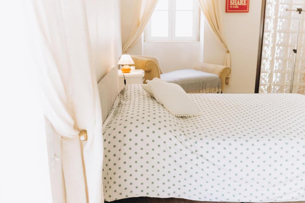 een slaapkamer met een bed met een witte sprei bij Casa das Pomegranates in Ílhavo