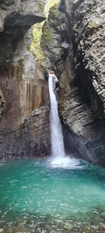 a waterfall in a canyon with a body of water at Apartma Soča Oasis in Srpenica