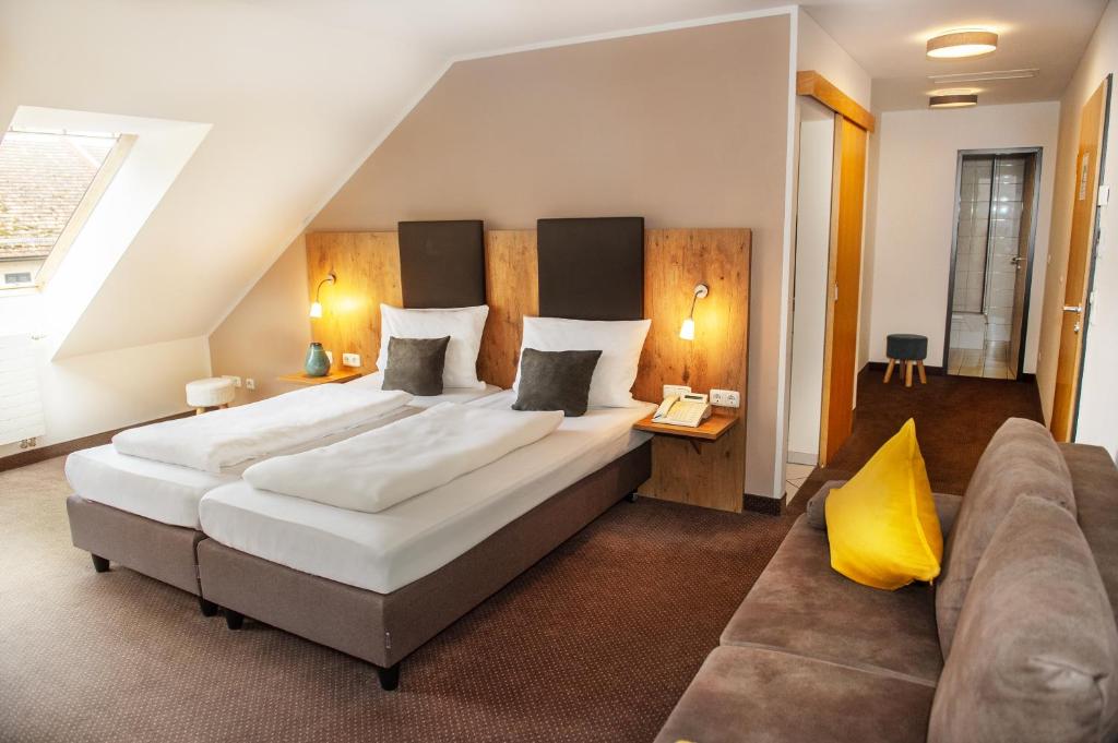 a large bedroom with a large bed and a couch at Hotel am Hachinger Bach by Blattl in Neubiberg