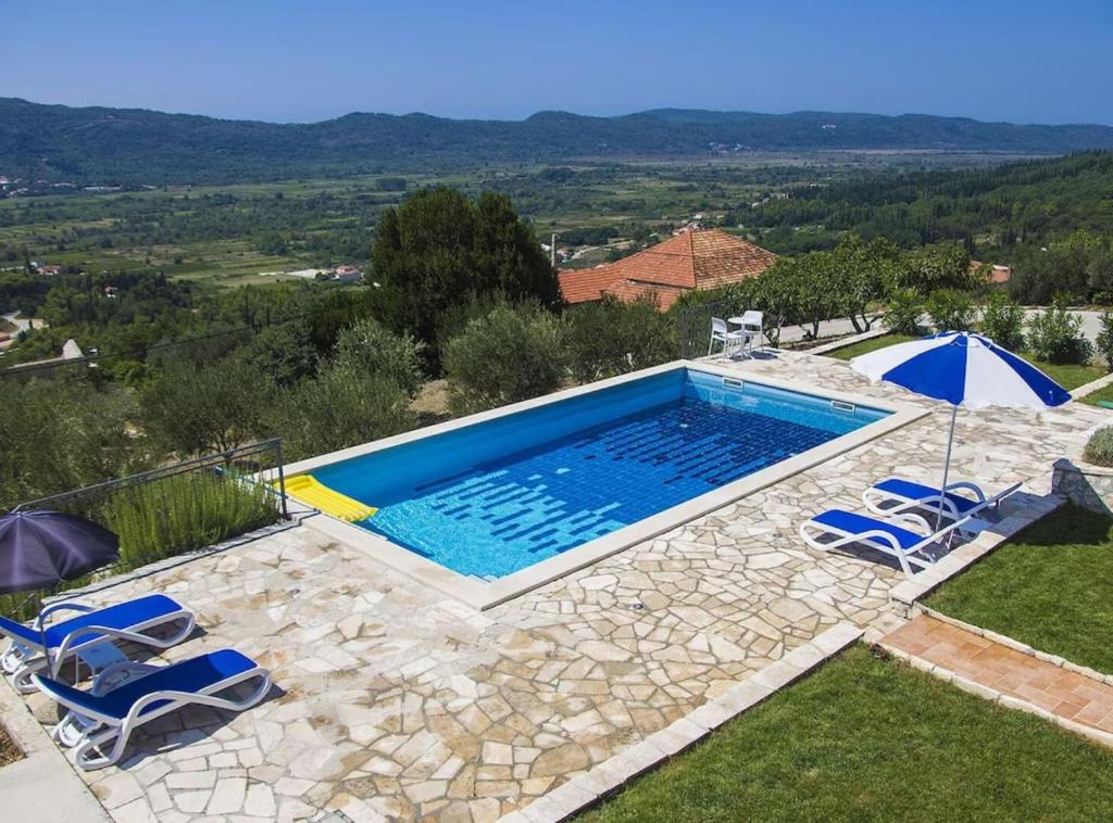 a swimming pool with two chairs and an umbrella at Villa Oliva in Gruda