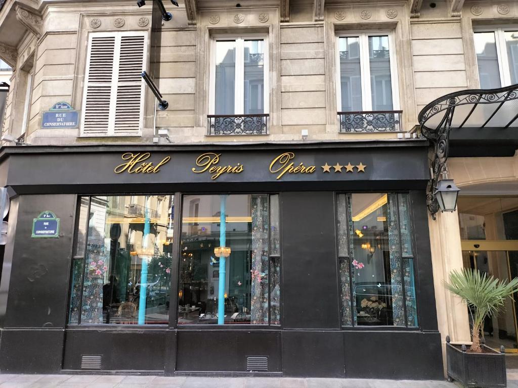 una tienda frente a un edificio con un cartel. en Hotel Peyris Opera, en París