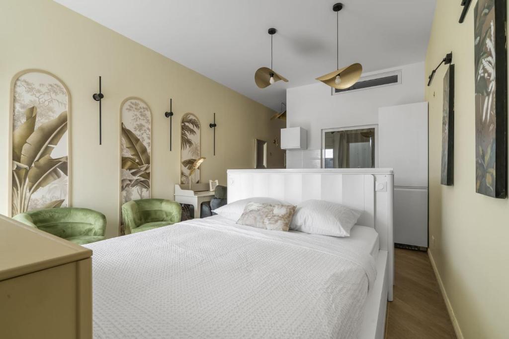 - une chambre avec un lit blanc et des chaises vertes dans l&#39;établissement Jardin Chic, à Fort-de-France