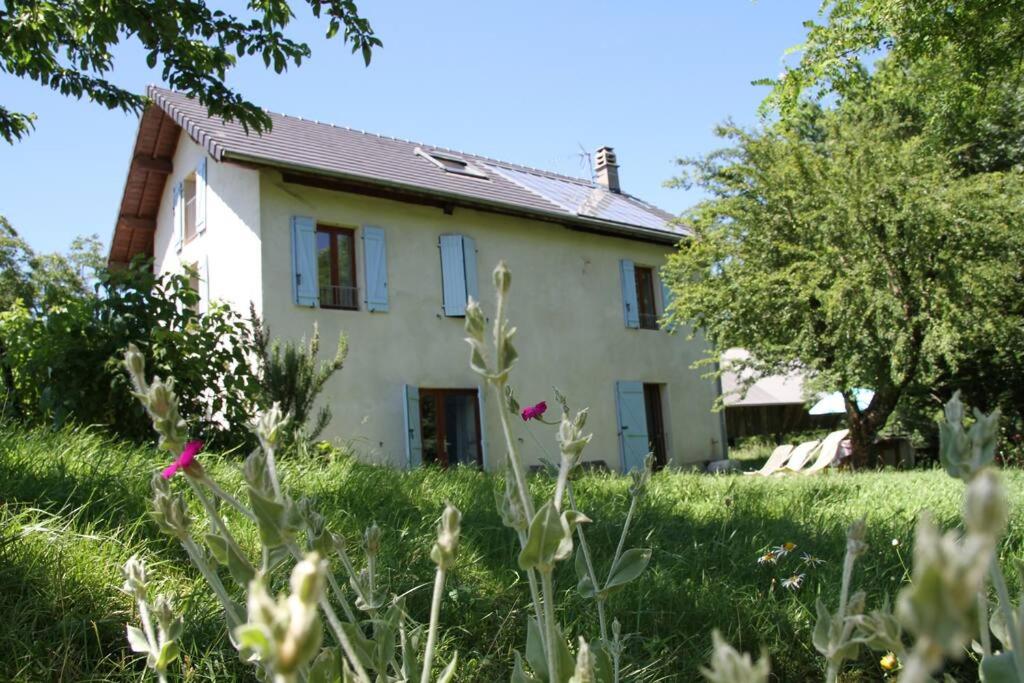 une maison blanche avec un champ d'herbe et de fleurs dans l'établissement Maison de campagne bucolique et ressourçante, à Sainte-Hélène-du-Lac