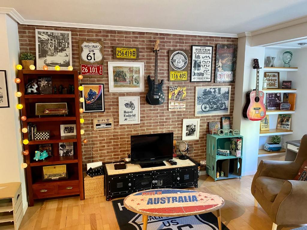 Apartamento estilo Vintage céntrico y garage incluido في لوغرونيو: غرفة معيشة مع جدار من الطوب مع تلفزيون