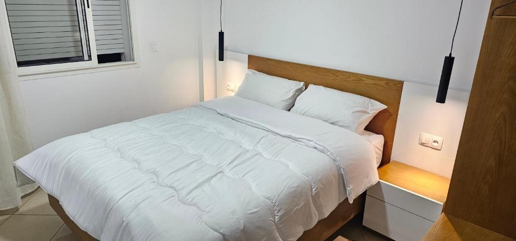 Una cama con sábanas blancas y almohadas en un dormitorio en La Paloma Blanca en Tetuán