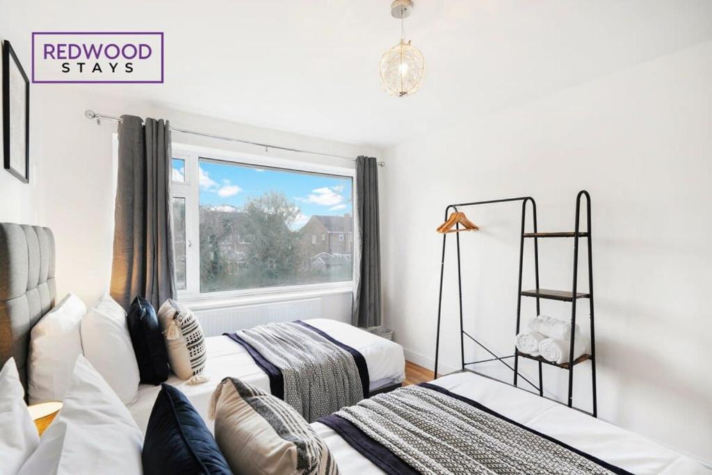una camera con due letti e una finestra di Cozy 3 Bed House with X2 FREE Parking By REDWOOD STAYS a Farnborough