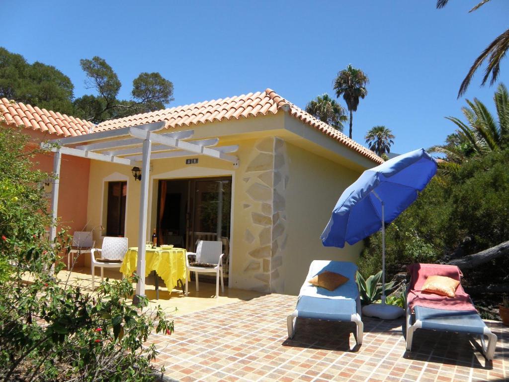ein Haus mit einem Tisch, Stühlen und einem Sonnenschirm in der Unterkunft Bungalows El Paradiso in Tazacorte