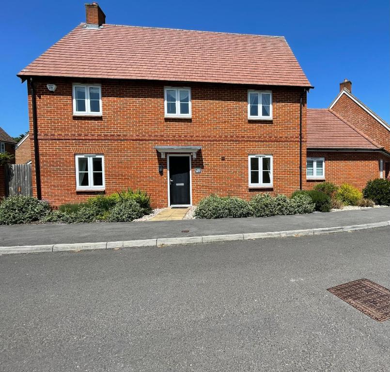 a red brick house on the side of a street at The Harrow Drive in Headley