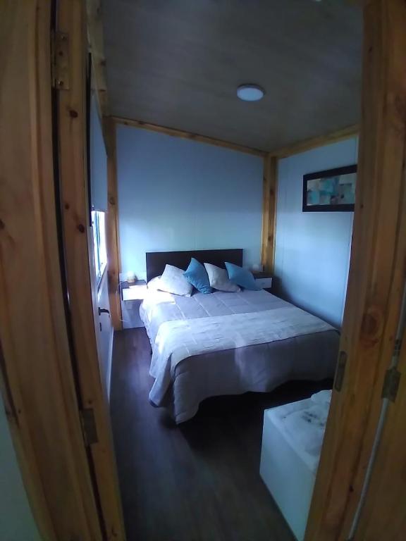 una camera da letto con un letto grande con lenzuola e cuscini bianchi di Tiny House Melgarejo a San Carlos de Bariloche