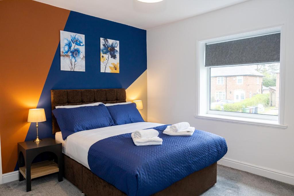 a bedroom with a blue and white bed and a window at AvenueHouse-BusinessReady-FREEParking&WIFI in Baguley
